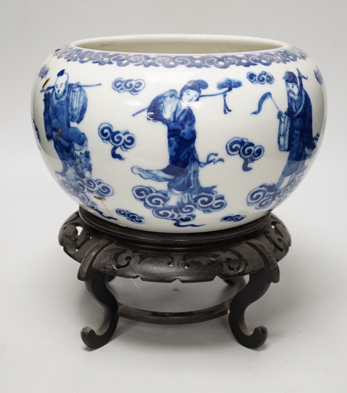 A 19th century Chinese blue and white ‘eight immortals’ alms bowl, apocryphal Qianlong seal mark, 25cm diameter (a.f.), wood stand